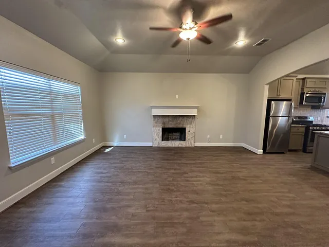 a view of a livingroom with a fireplace a ceiling fan and window