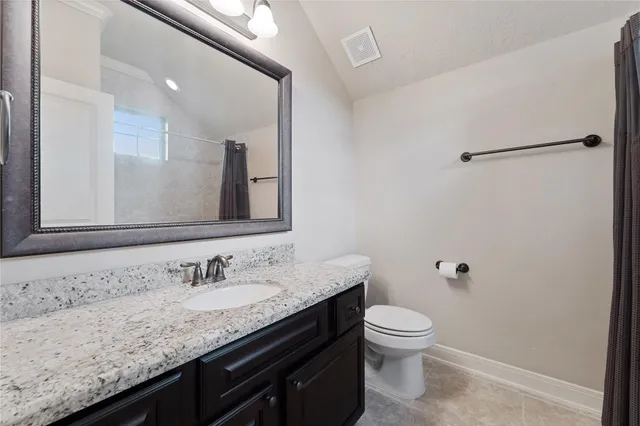 a bathroom with a granite countertop sink a toilet and a mirror