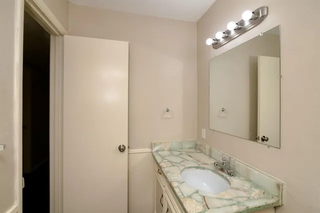 a bathroom with a granite countertop sink and a mirror