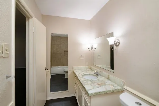 a bathroom with a granite countertop double vanity sink and mirror