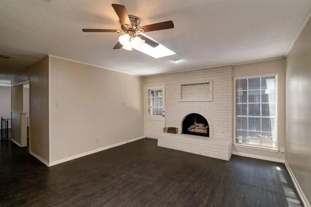 an empty room with wooden floor fireplace and windows