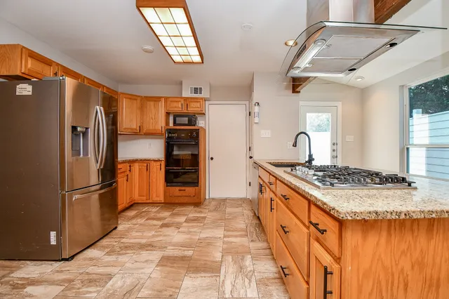 a large kitchen with stainless steel appliances granite countertop a sink and cabinets