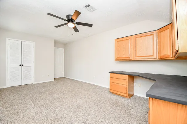 an empty room with windows and ceiling fan