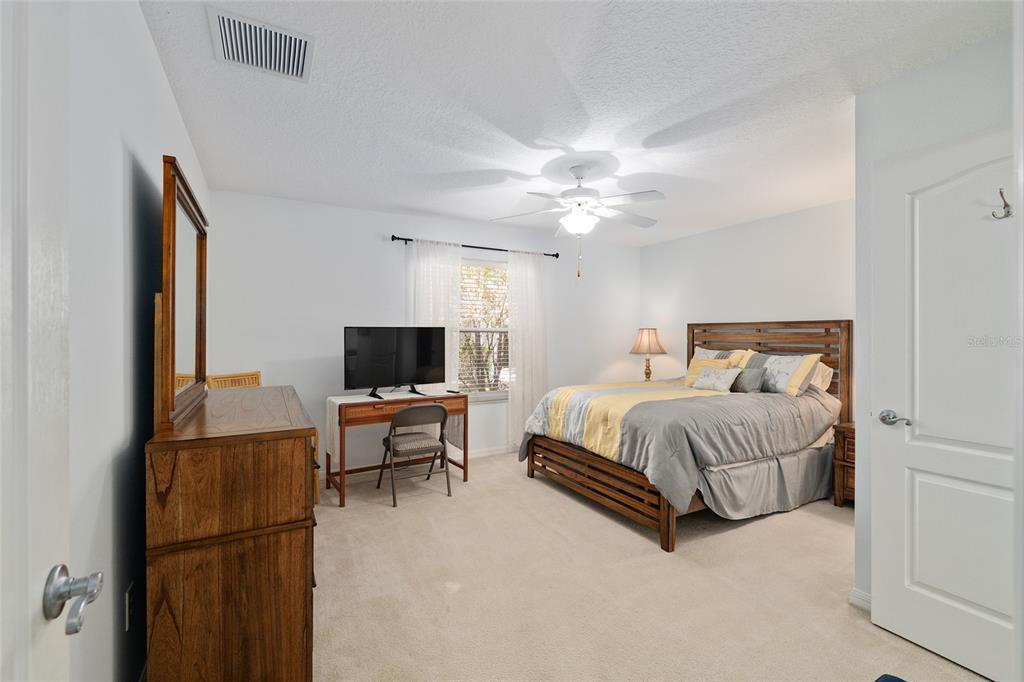 3073 Riverdale Road The Villages, FL 32162 - Photo 25 of 38 a spacious bedroom with a bed and a chandelier