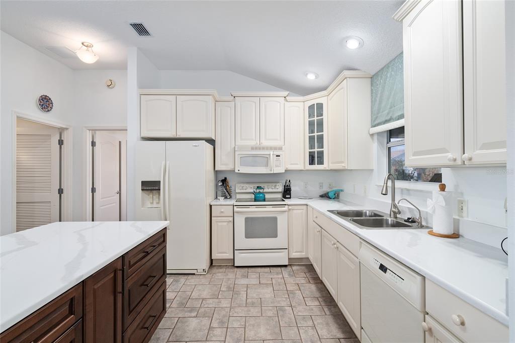 3073 Riverdale Road The Villages, FL 32162 - Photo 9 of 38 a kitchen with white cabinets and white appliances