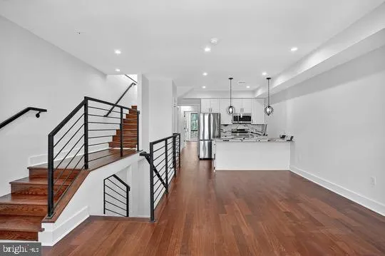a kitchen with a refrigerator a oven and a wooden floor