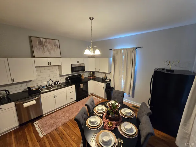 a kitchen with stainless steel appliances granite countertop a refrigerator a stove a microwave and a dining table with wooden floor