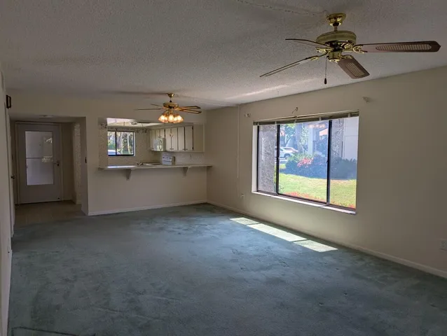 an empty room with a chandelier fan and windows
