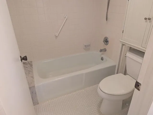 a white toilet sitting next to a bath tub