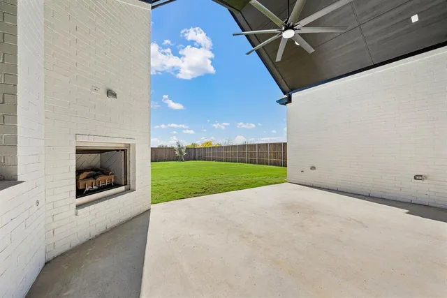 a view of a livingroom with a fireplace a ceiling fan and a kitchen view