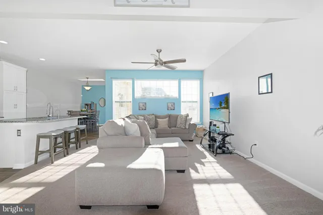a living room with furniture a large window and white appliances