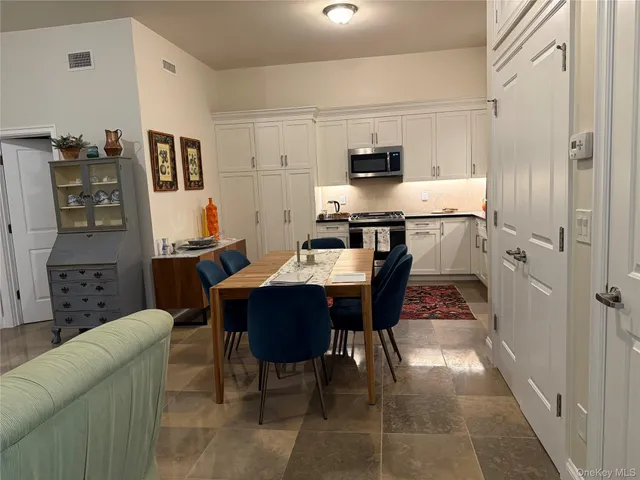 a kitchen with stainless steel appliances kitchen island granite countertop a refrigerator a stove a sink a dining table and chairs with wooden floor