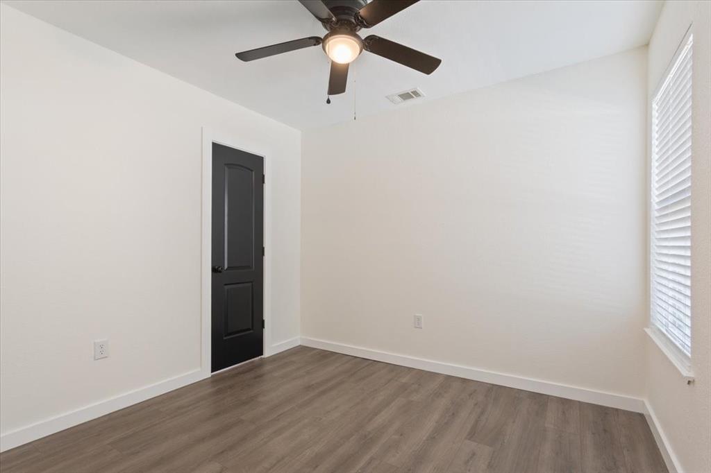 108 Private Road Whitney, TX 76692 - Photo 10 of 36 First primary bedroom #1. Room featuring wood-finish flooring, crisp white walls, and a contemporary dark-paneled door with white trim