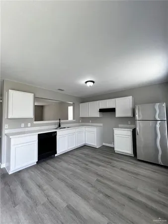 a large kitchen with stainless steel appliances granite countertop a stove a sink dishwasher and a refrigerator with wooden floor