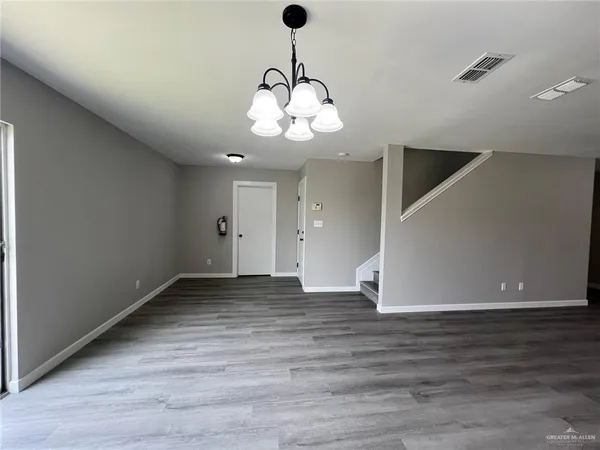 a view of an empty room with wooden floor and windows