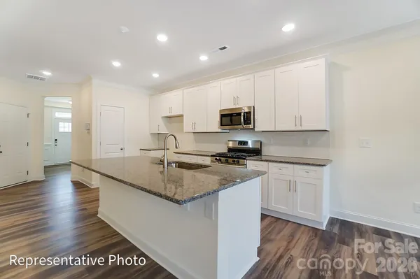 a kitchen with stainless steel appliances granite countertop a sink a stove a microwave a sink a refrigerator and cabinets