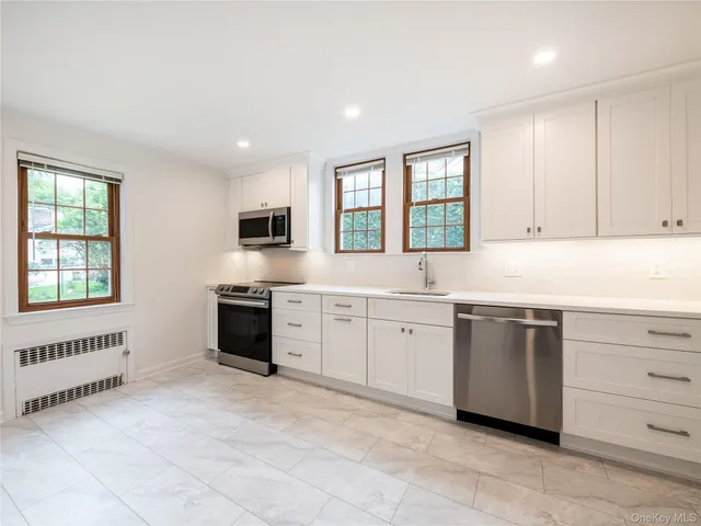a kitchen with granite countertop white cabinets stainless steel appliances a sink and a window