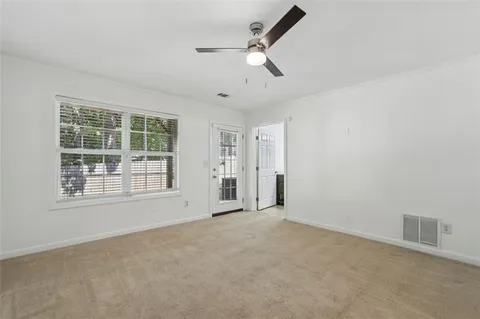 an empty room with chandelier fan and windows