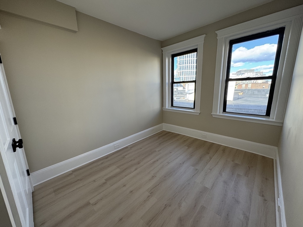 41 Edgerly Road, Unit 22 Boston, MA 02115 - Photo 8 of 13 an empty room with wooden floor and windows