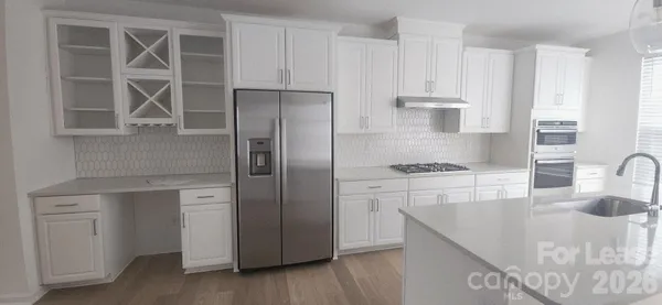 a kitchen with stainless steel appliances granite countertop a sink a stove and a refrigerator with wooden floor