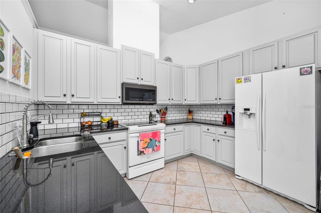 5154 Southwest 88 Terrace Gainesville, FL 32608 - Photo 10 of 29 a kitchen with stainless steel appliances a refrigerator sink and white cabinets
