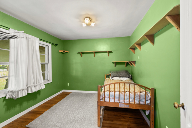658 North 100 East Logan, UT 84321 - Photo 10 of 26 Bright room featuring wood-finish flooring, a white trim baseboard, a window with a white frame, and multiple wall-mounted shelving units