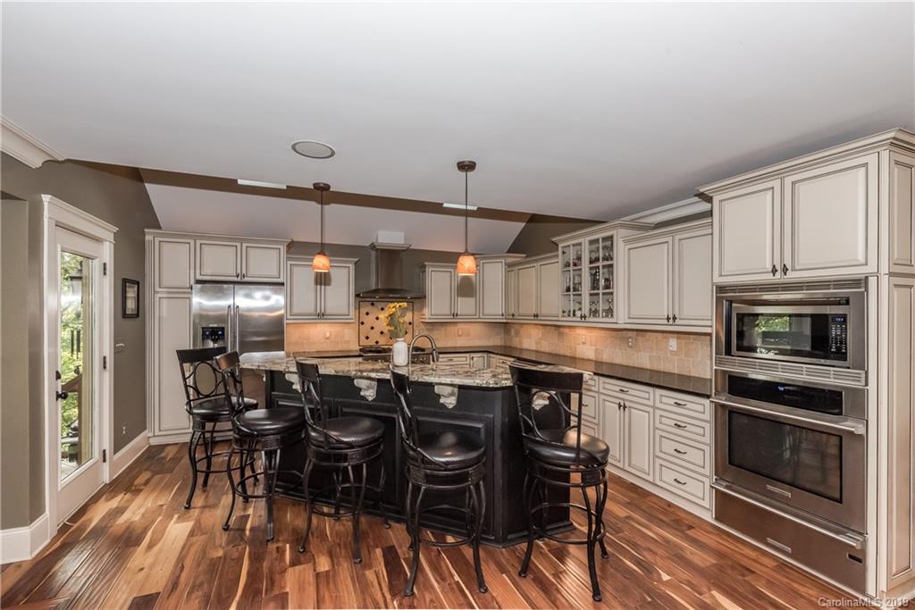 10023 Bora Bora Drive Tega Cay, SC 29708 - Photo 9 of 32 a kitchen with lots of wooden furniture and stainless steel appliances