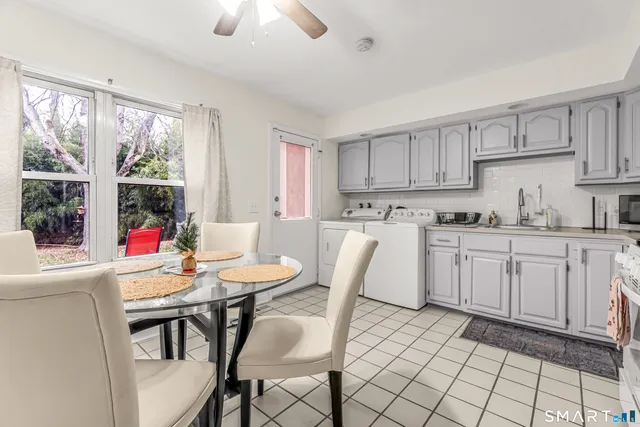 a kitchen with a dining table chairs and white appliances