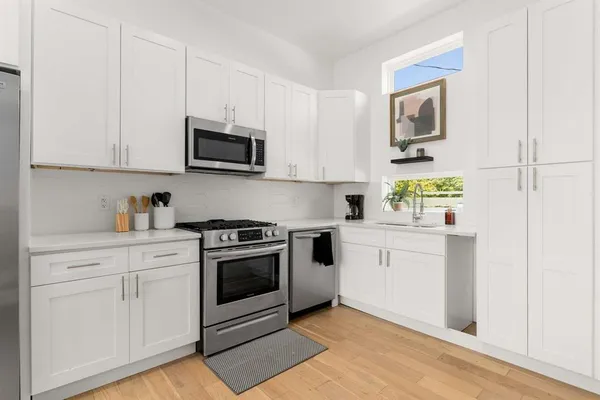 a kitchen with white cabinets and appliances