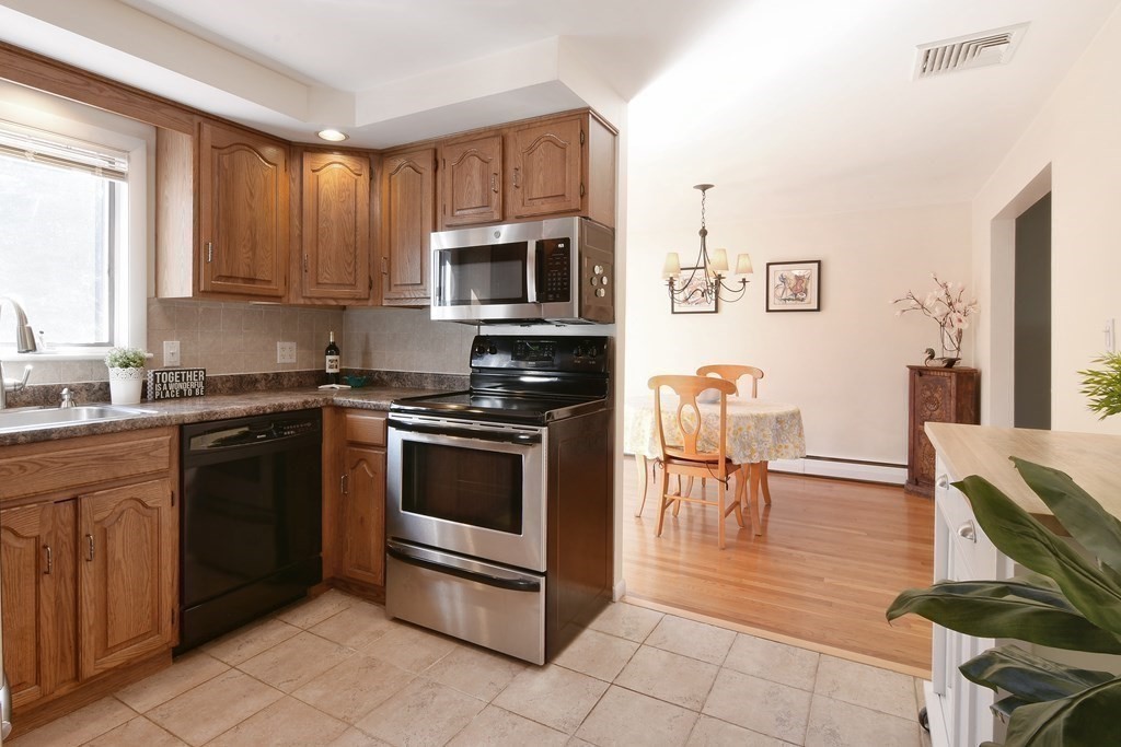 130 Florence Road Waltham, MA 02453 - Photo 5 of 26 a kitchen with stainless steel appliances granite countertop a stove top oven a sink a dining table and chairs
