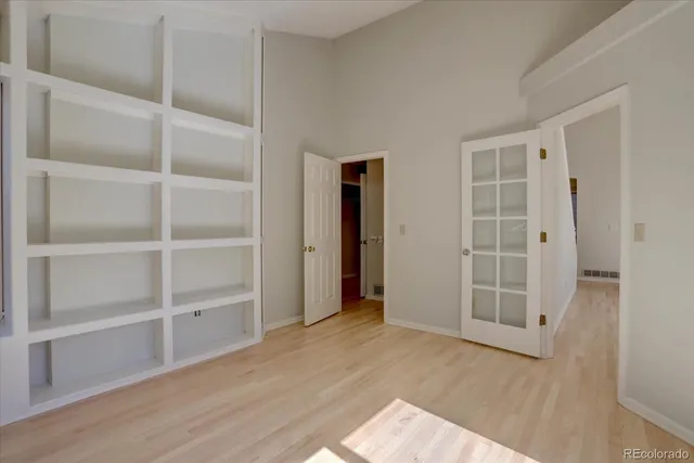 a view of an empty room with wooden floor and closet