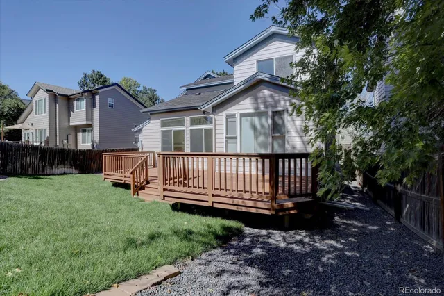 a view of a house with a yard and wooden deck