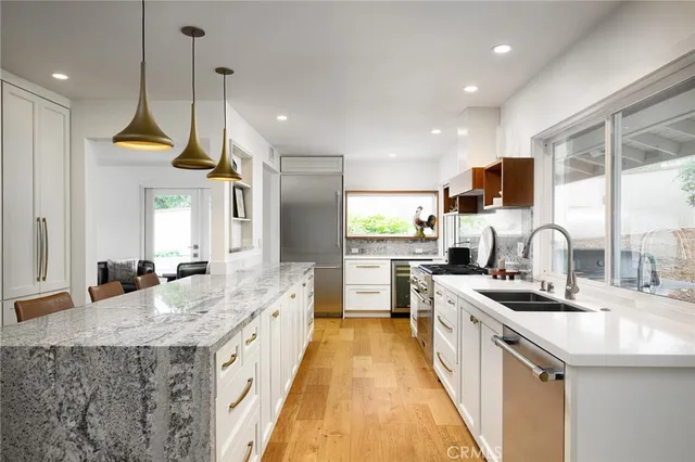 a large kitchen with stainless steel appliances kitchen island granite countertop a sink and a wooden floors