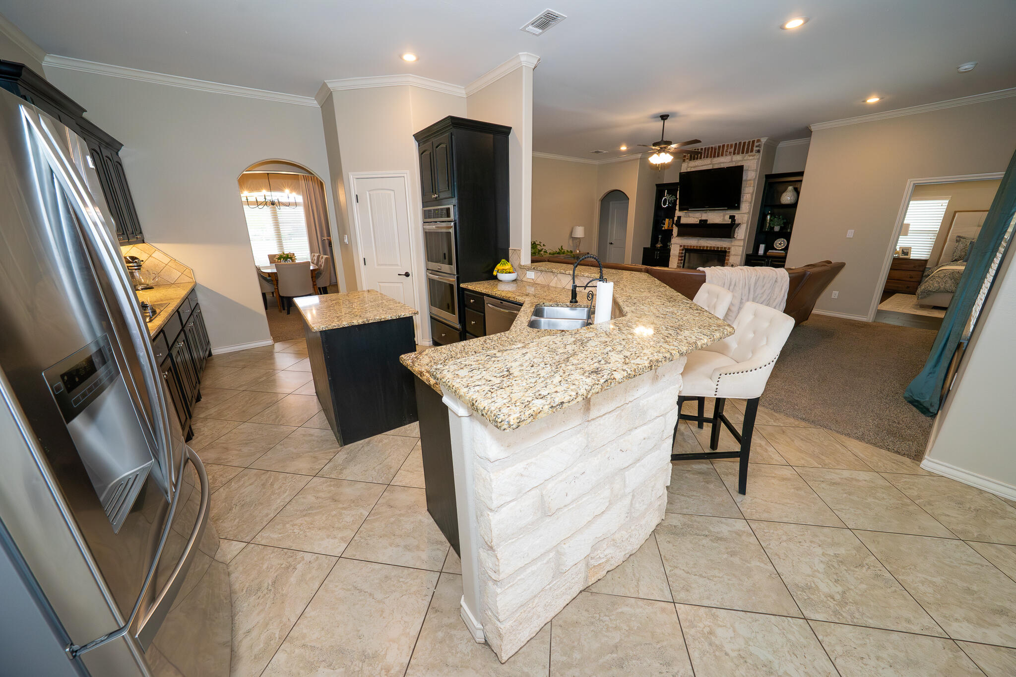 3301 County Road 7560 Lubbock, TX 79423 - Photo 10 of 40 a large kitchen with stainless steel appliances kitchen island granite countertop a table chairs and a refrigerator