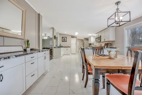 a kitchen with stainless steel appliances granite countertop a table chairs sink and cabinets