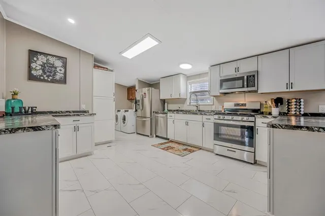 a kitchen with white cabinets and appliances