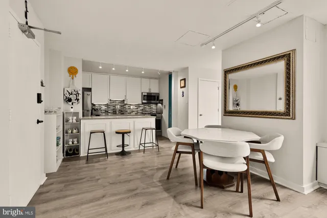 a kitchen with stainless steel appliances kitchen island granite countertop a table chairs and a refrigerator