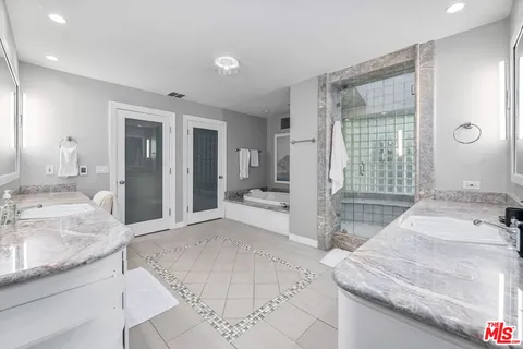 a spacious bathroom with a granite countertop double vanity sink a mirror and a bathtub