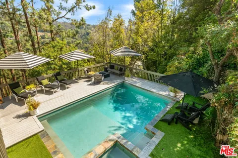 a view of a swimming pool with lawn chairs under an umbrella
