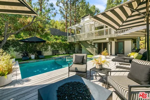 a view of a patio with couches table and chairs under an umbrella