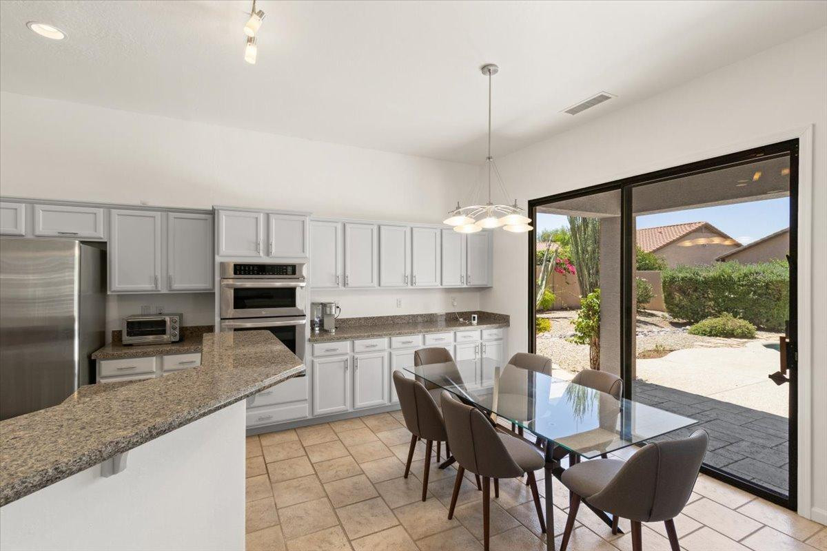 4211 East Kirkland Road Phoenix, AZ 85050 - Photo 4 of 23 a kitchen with kitchen island granite countertop a table chairs microwave and refrigerator