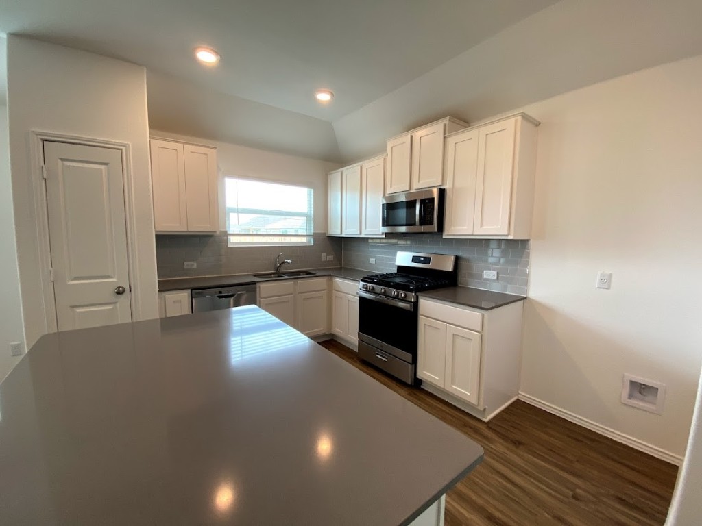 3106 Kenner Drive Pflugerville, TX 78660 - Photo 5 of 11 a kitchen with granite countertop a stove a sink and a refrigerator