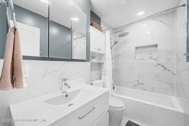 a bathroom with a bathtub shower sink mirror vanity and toilet