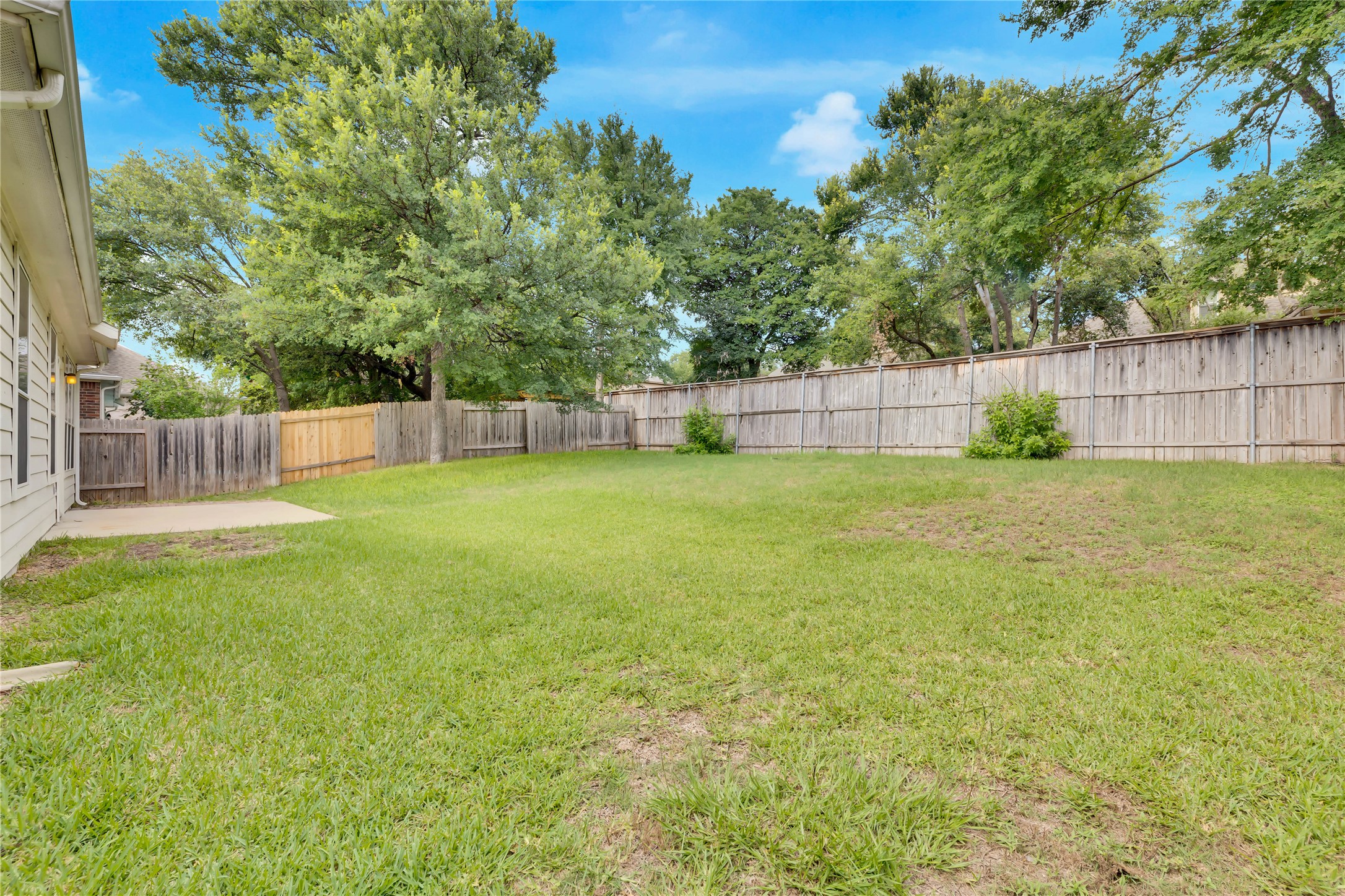 2133 Paradise Ridge Drive Round Rock, TX 78665 - Photo 21 of 22 Expansive grassed yard with a concrete patio, wood privacy fencing, and mature perimeter trees