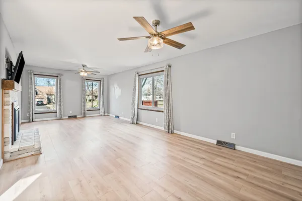 a view of an empty room with window and wooden floor