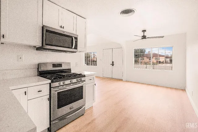 a kitchen with stainless steel appliances a stove a microwave and white cabinets