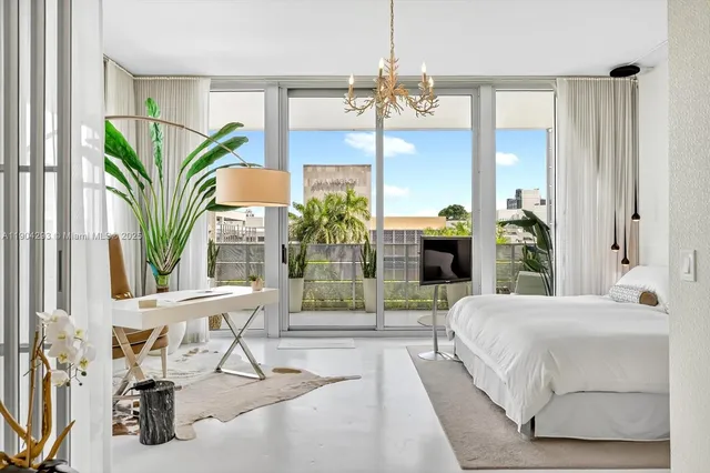 a bedroom with a bed a chandelier and large window