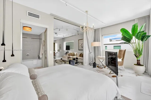 a bedroom with a bed a potted plant on the dresser and a chandelier
