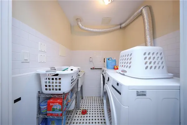 a utility room with fridge and wooden floor