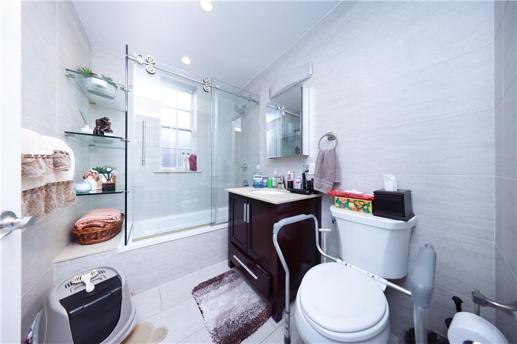 8785 14th Avenue, Unit 1B Brooklyn, NY 11228 - Photo 10 of 29 a white toilet sitting next to a bathroom sink and vanity